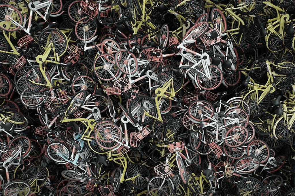 Abandoned bike sharing bicycles piled in chaotic urban waste heap.